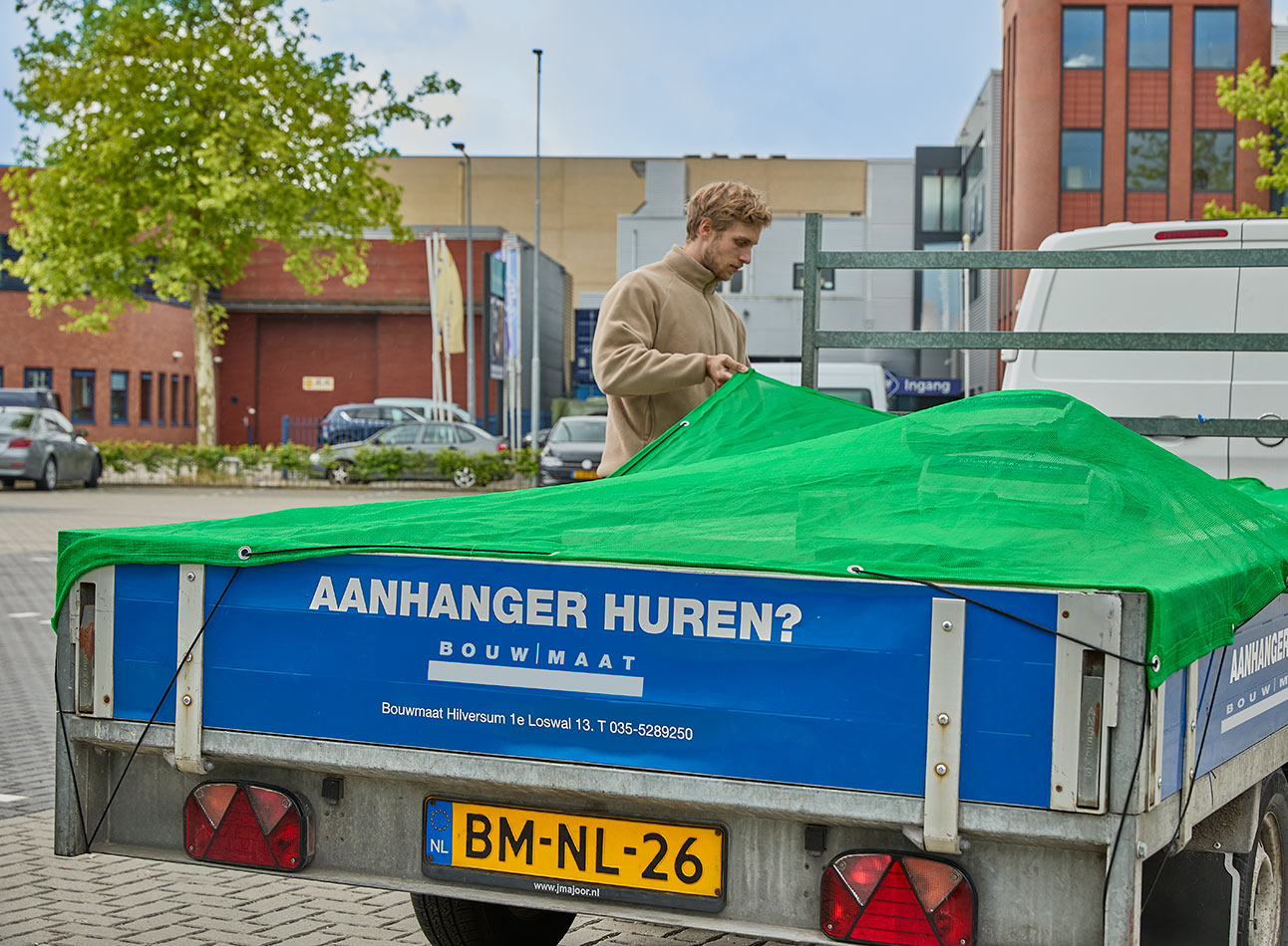 vakman plaatst zeil over aanhanger bij Bouwmaat vestiging
 - article 2