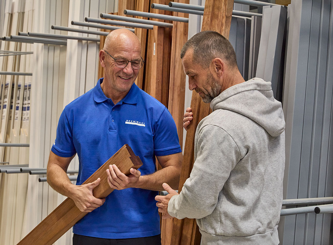 medewerker en vakman bekijken kozijnprofiel in showroom
 - article 3