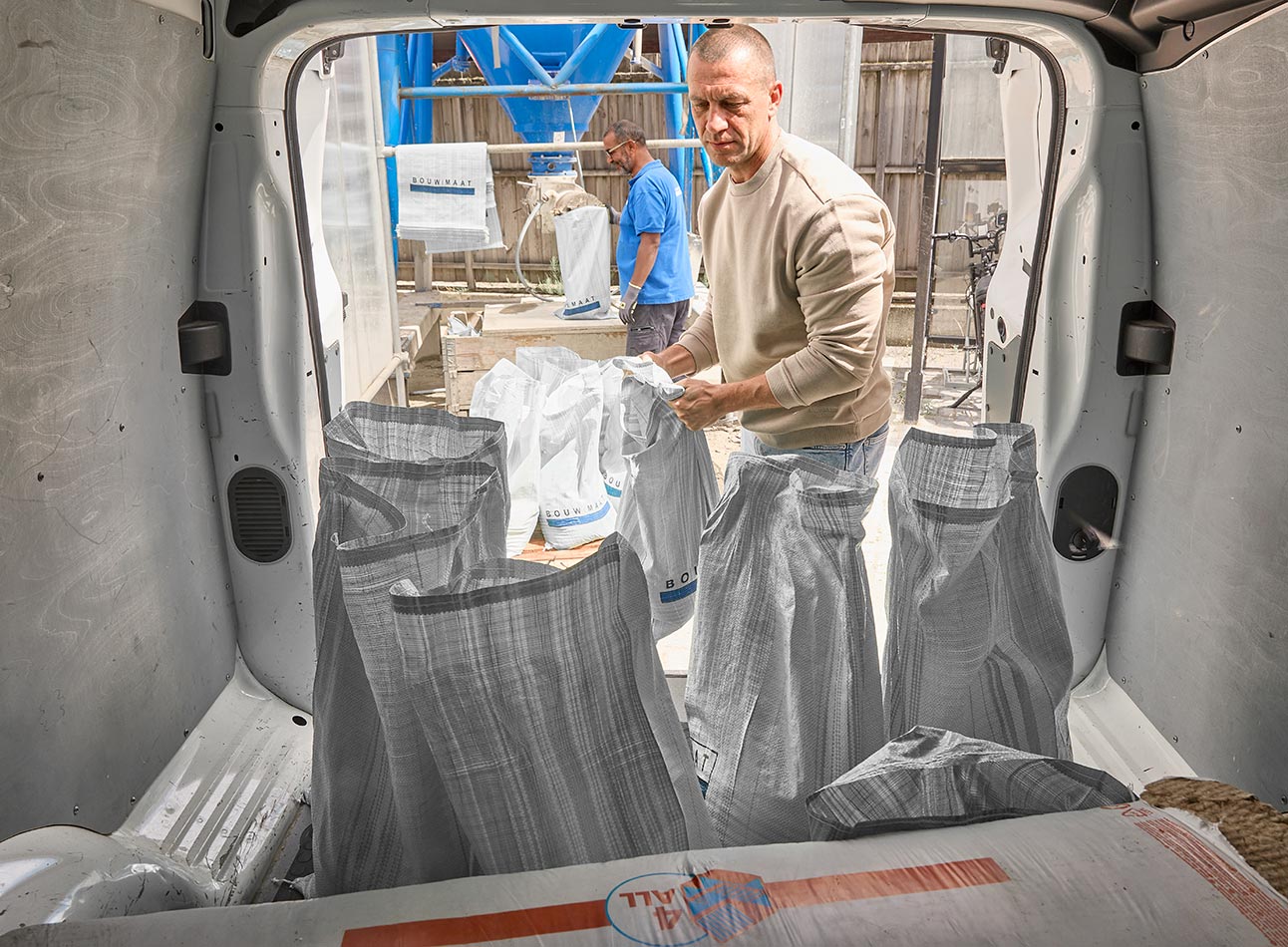 vakman staat bij gevulde speciezakken in laadruimte van bus
 - article 1