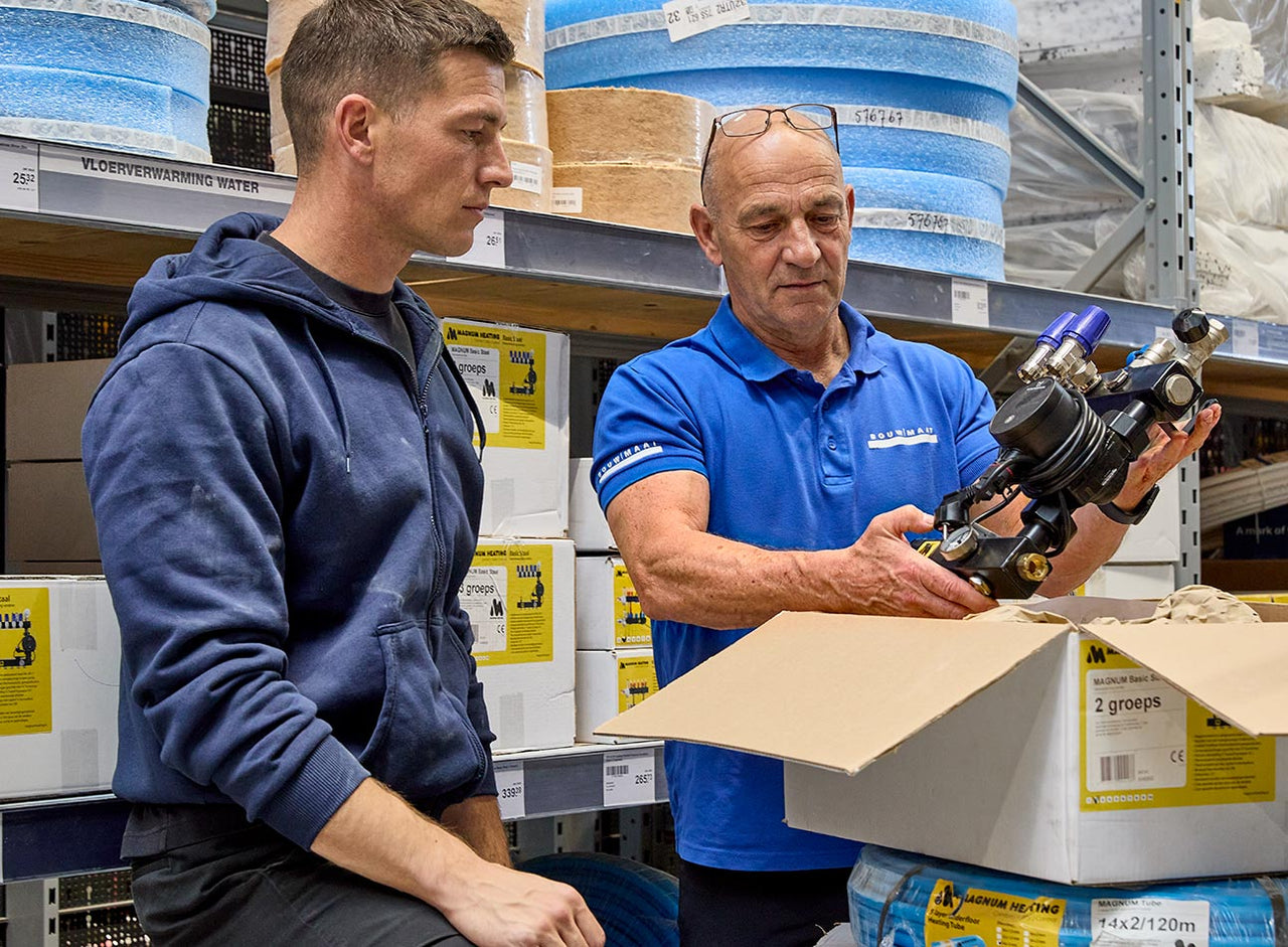 medewerker toont vloerverwarmingsonderdeel aan vakman in magazijn
 - service media