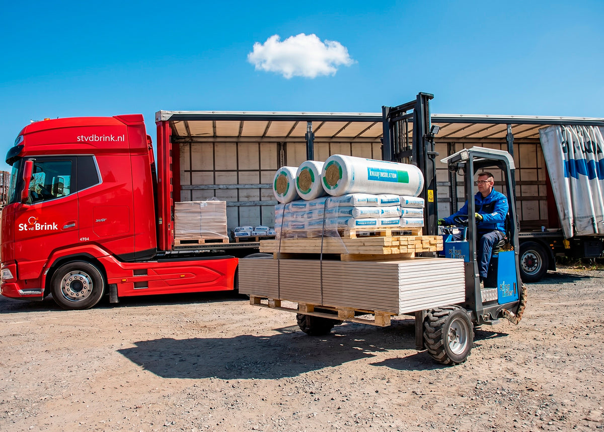 Bouwmaterialen worden met een heftruck uit een vrachtwagen gelost voor bezorging