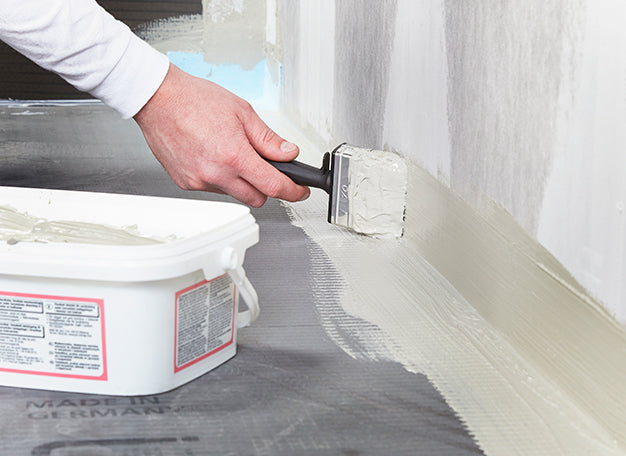 Vakman brengt waterdichte coating aan op de vloer van een natte cel als voorbereiding op het tegelen - media 2