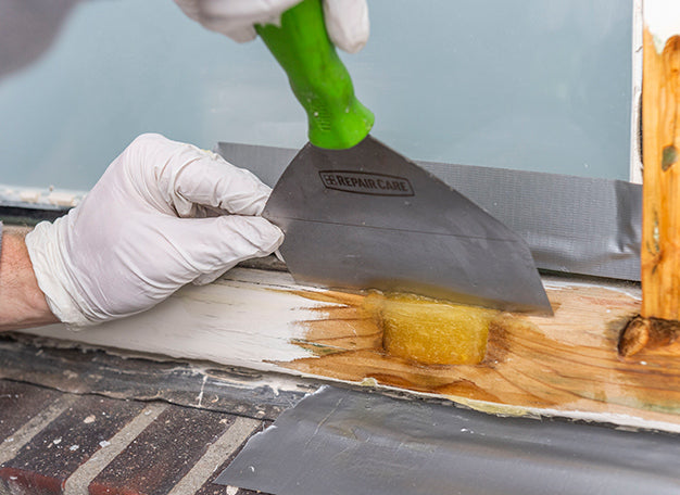 Vakman werkt een houtrotreparatie af met reparatiemiddel op een houten buitenkozijn - media 2