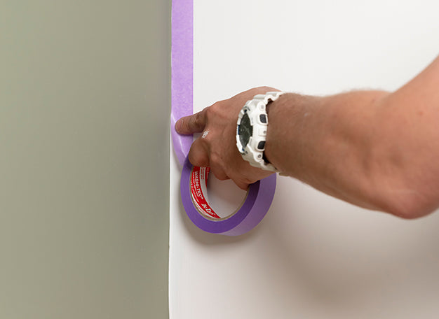 Vakman is de schilderklus aan het voorbereiden door een muur af te plakken met schilderstape - media 3